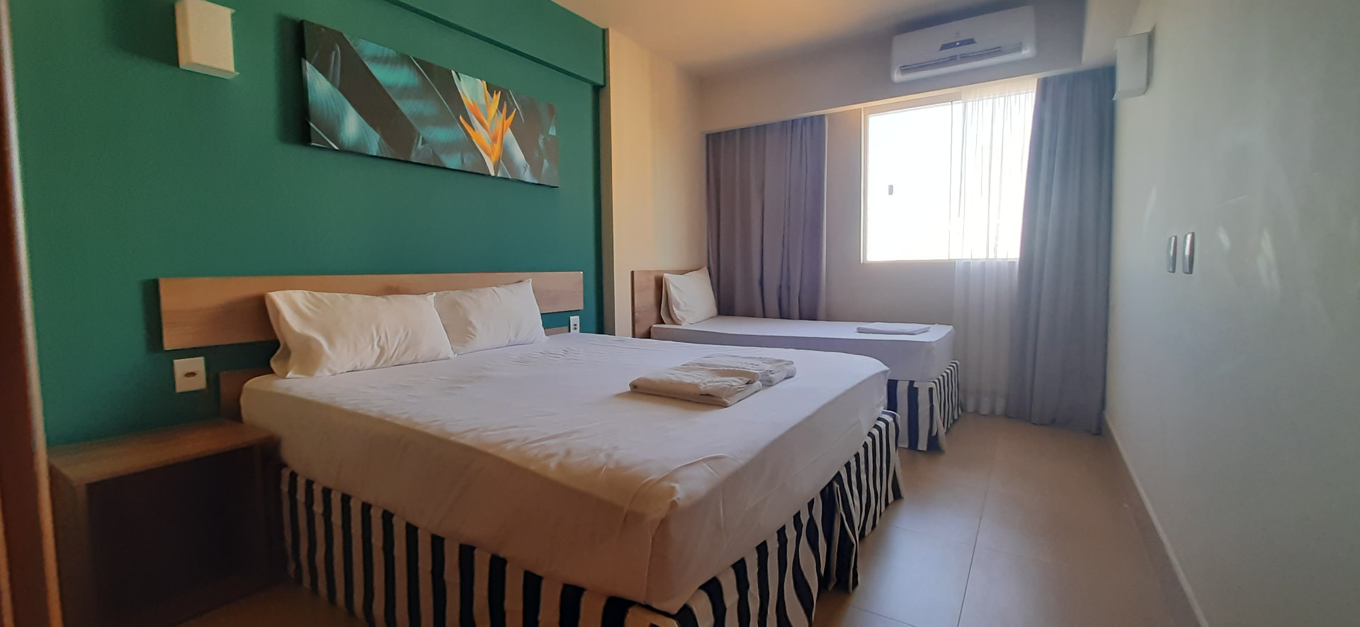 Quarto com cama de casal e cama de solteiro junto à janela