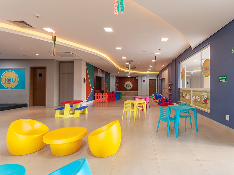 Espaço kids club com brinquedos e mesas coloridas