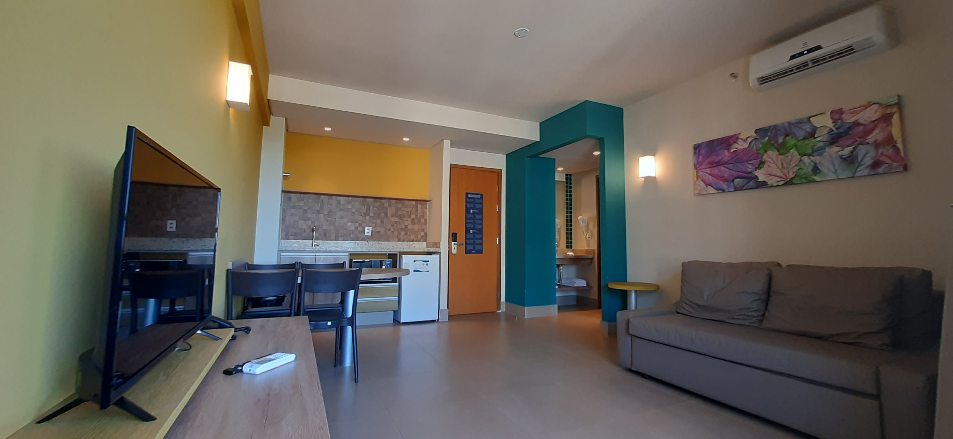 Sala do apartamento com TV, sofá-cama e cozinha americana